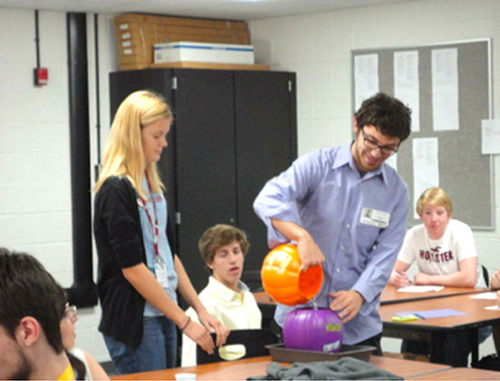 TNT Physics major Gene Costa performs an experiment illustrating buoyancy with a group of high school students.
