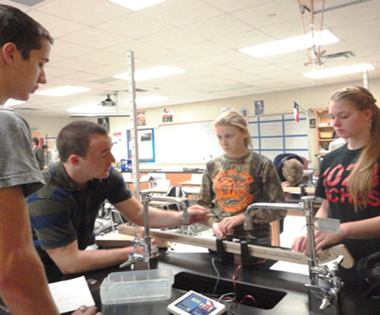 TNT Physics major Johnny Long works with a force-motion track during an experiment with local high school students.